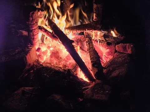 Flames of a stone pit fire at night in dark background at a campground Stock Photos
