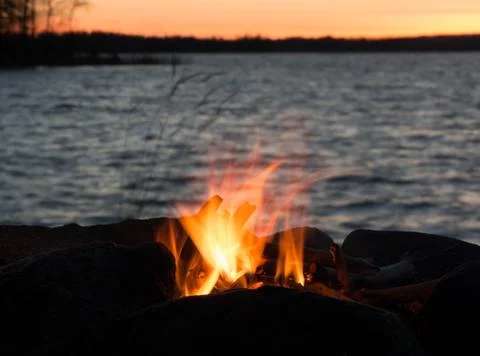 Flaming campfire at evening lake Stock Photos