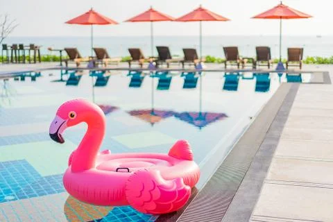 Flamingo float around swimming pool in hotel resort with umbrella and chair i Stock Photos