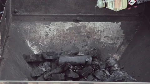 Flammable Liquid Is Poured On Coals For The Grill. Hand Holds Bottle Of Liquid. Stock Footage 236689202