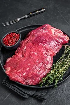 Flank or flap raw beef steak on plate with thyme. Black background. Top view Stock-Fotos