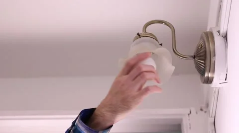Flannel sleeved hand changes light bulb in stairwell Stock Footage 48044525
