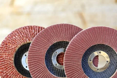 Flap grinding wheels of different grains on wood and metal on a light beige.. Stock Photos