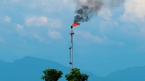 A flare stack burning off excess gas at an oil refinery with copy space in Stock Footage 279531732