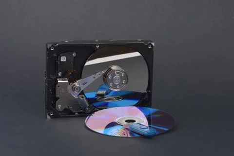 Flash card lying on a disk and a opened hard disk on  dark grey background Stock Photos