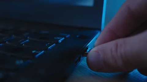 Flash drive being plugged into laptop computer by spy or hacker in dark room Stock Footage 334734227