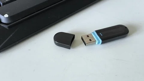 Flash drive with a cap on the table near the laptop keyboard. Storing data on a Video stock 320523676