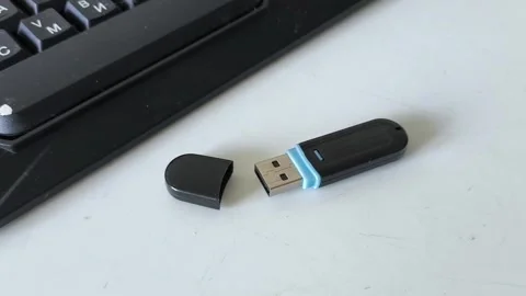 Flash drive with a cap on the table near the laptop keyboard. Storing data on a Stock Footage 320523682