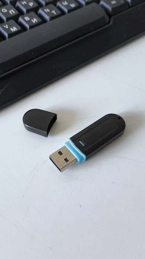 Flash drive with a cap on the table near the laptop keyboard. Storing data on a Stock Footage 320523693