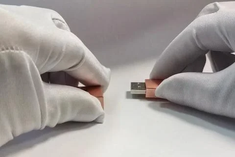 Flash drive in hands in white gloves. Storage of information on flash drive. Foto stock