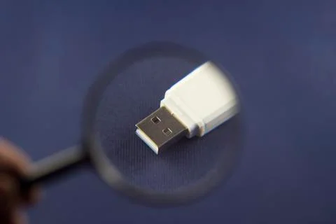 Flash drive under magnification through magnifier, blue background Stock Photos