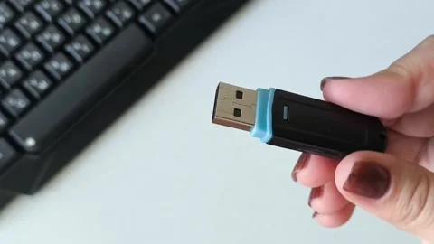 Flash drive in a womans hand against the background of a laptop keyboard. Data Stock Footage 320523561