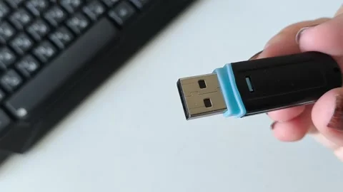 Flash drive in a womans hand against the background of a laptop keyboard. Data Stock Footage 320523593