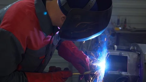 Flashes of blue flame from welding, man in protective helmet conducts welding Stock Footage 120064757