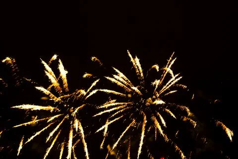 Flashes of bright golden firework figures on the black night sky. Stockfoto's