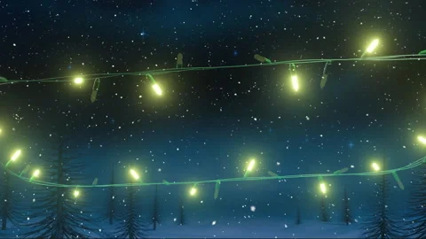 Flashing yellow christmas string lights over falling snow and tree tops on night Stock Footage 310924739