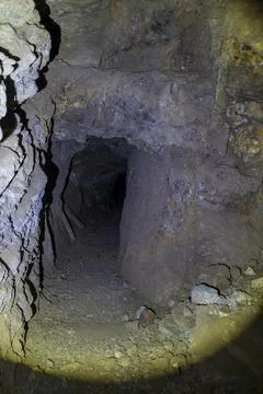 Flashlight beam illuminates an old mine shaft with timbers leaning against th Stock Photos