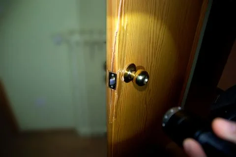 A flashlight illuminates the lock on a forced door robbery at home Stock Photos