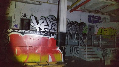 Flashlight lighting up ahead of moving camera in vacant factory Vidéo 88415939