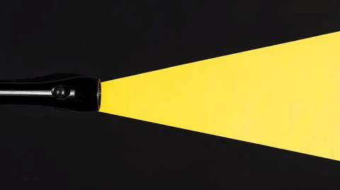 Flashlight shining on a dark background, flat lay. Light beam made of paper. Stock Photos