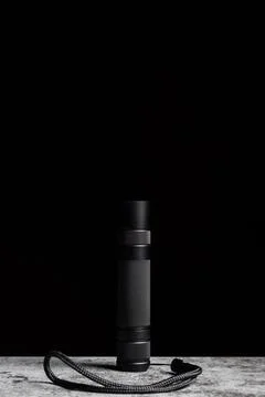 Flashlight stands on a table on a black background with vertical copy space Stock Photos