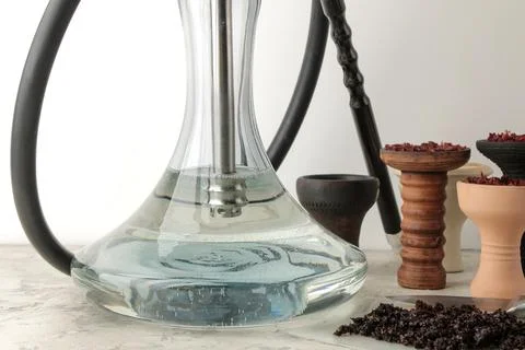 Flask and accessories for making hookah, clay bowls and tobacco on a light ba Stock Photos
