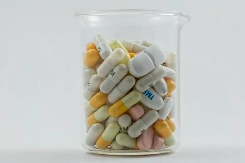 Flask full of pills of different sizes isolated on a white background Stock Photos