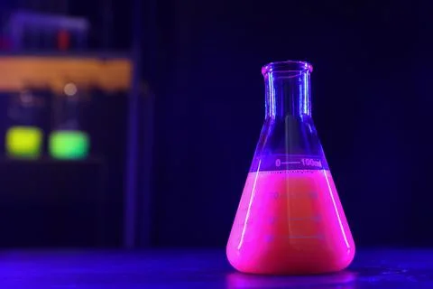 Flask with luminous liquid on table in laboratory, space for text Stock Photos