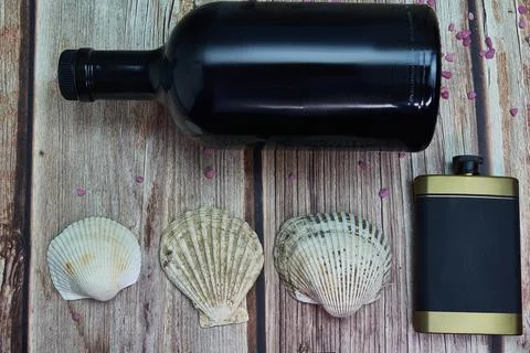 Flask sea shells and a bottle of alcohol on wood Stock Photos
