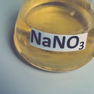 Flask of sodium nitrate with solution, on a gray background. Stock Photos