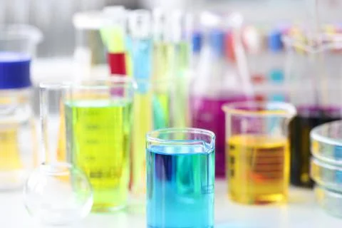 Flasks and test tubes with multicolored liquid standing on table in laboratory Stock Photos