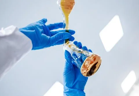 Flasks with brown liquid in scientist hands with dropping chemical liquid to Fotos de archivo