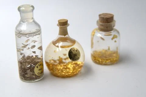 Flasks containing gold samples of varying caliber. Stock Photos