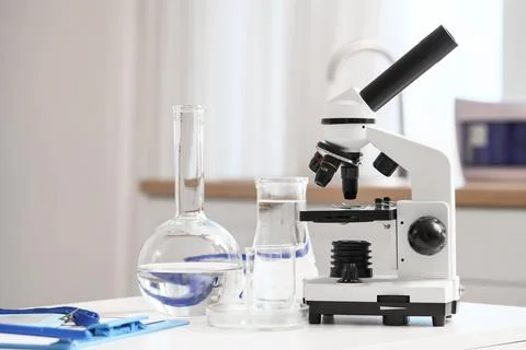 Flasks with water samples and microscope on table in laboratory Фото