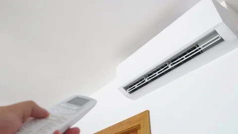 Flat air conditioner on white wall in room interior. Man pushing button on Stock Footage 127943839