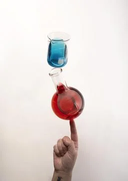 Flat bottom flask and a Berzelius beaker glass balanced on top of fingertip Stock Photos