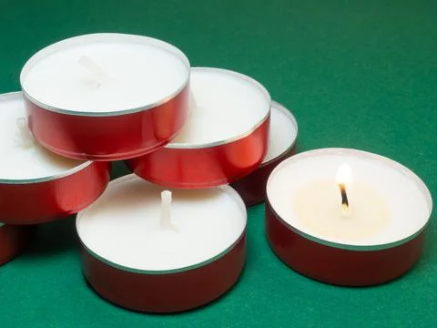 Flat candles on the table. Small candles on a green background. Candles not b Stock Photos