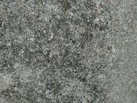 A flat, coarse concrete surface exhibits a speckled appearance filled with .. Stock Photos