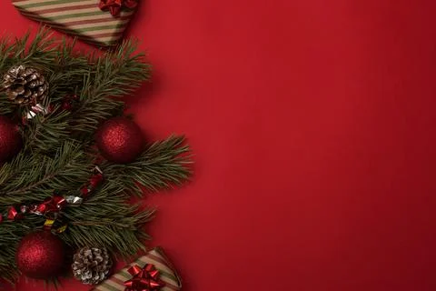 Flat composition with fir branches, cones and red balls on a red background Stock Photos