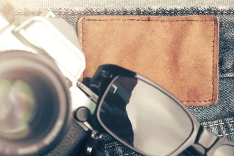Flat composition of vintage SLR camera and sunglasses on worn jeans Stock Photos