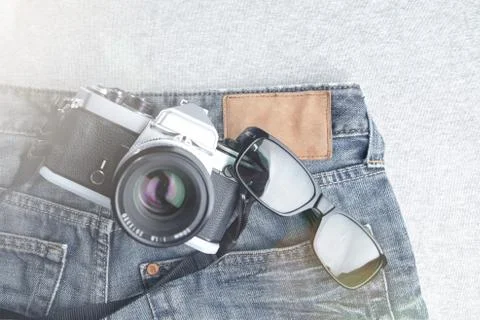 Flat composition of vintage SLR camera and sunglasses on worn jeans Stock Photos