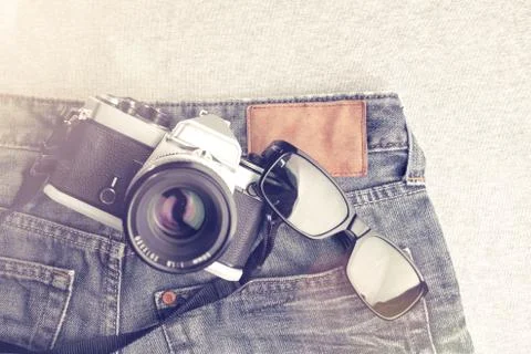 Flat composition of vintage SLR camera and sunglasses on worn jeans Stock Photos