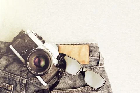 Flat composition of vintage SLR camera and sunglasses on jeans and grey fabric Stock Photos