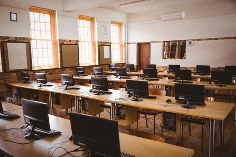 Flat design computer classroom is showing wooden desks with monitors, keyboards Stock Photos