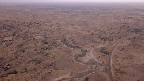 Flat dry land with baobab trees and small bushes, road passing in middle Video stock 208937050