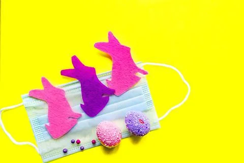 Flat easter composition rabbits and colored eggs on medical mask Stock Photos
