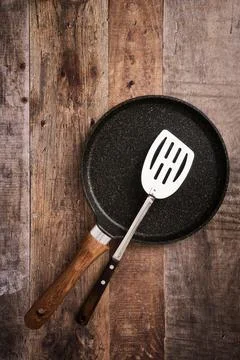 Flat large pancake baking pan and kitchen steel spatula, wood background with Stock Photos