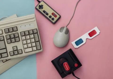 Flat lay 80s attribute composition. PC keyboard, mouse, gamepads, 3D glasses. Stock Photos