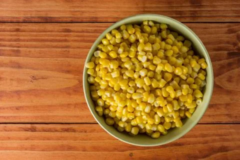 Flat lay above bowl with cooked corn on the wooden table Stock Photos