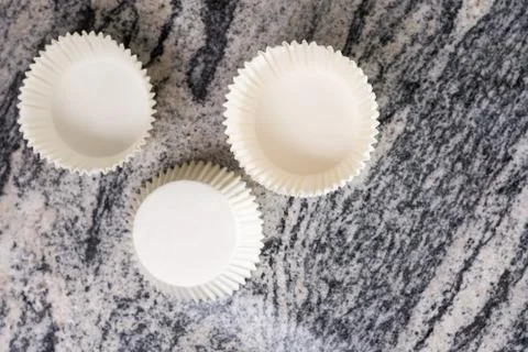 Flat lay above empty white cup cake cases containers on the grey granite marb Stock Photos